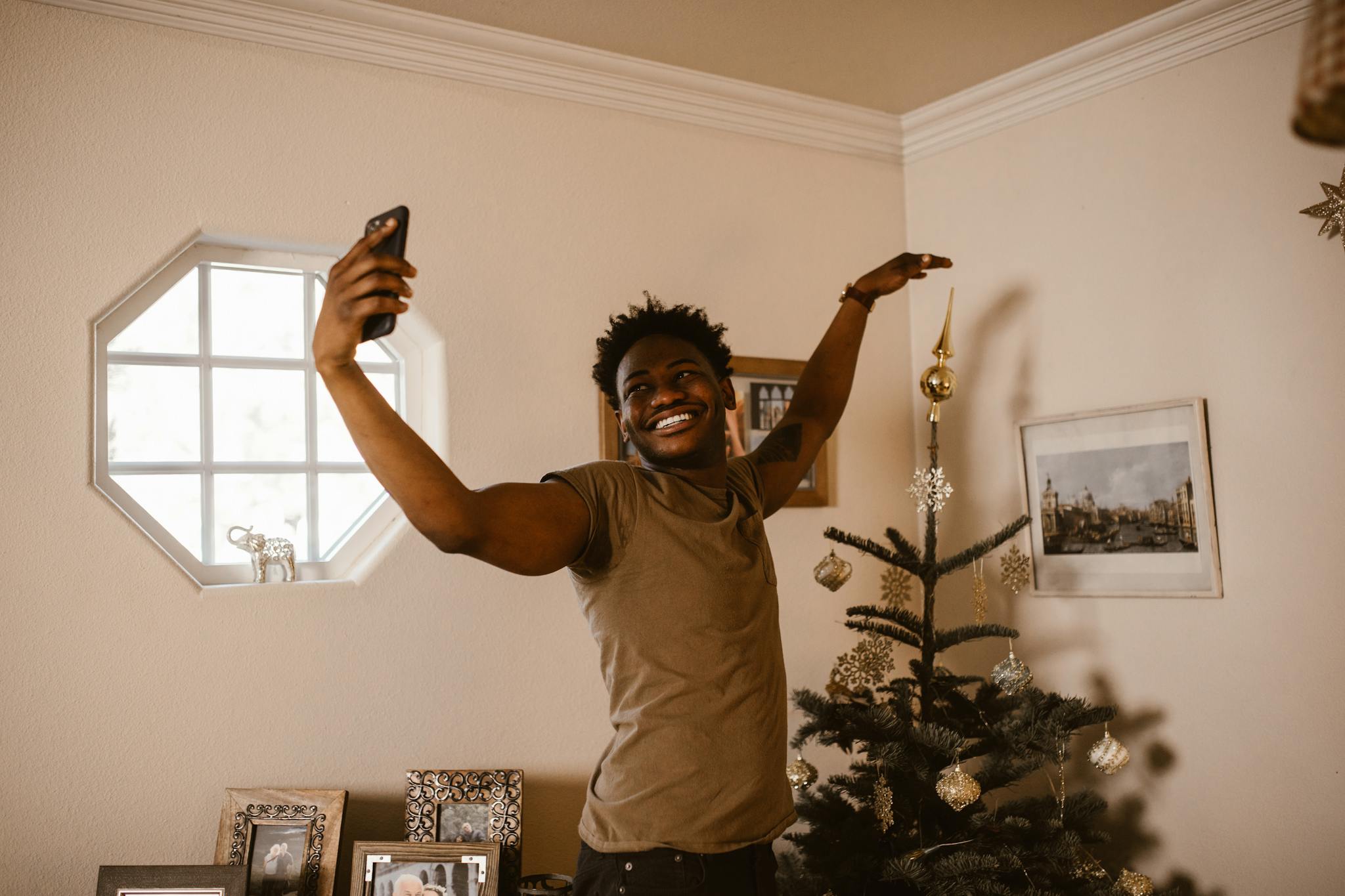 Smiling man making a video call indoors, enjoying festive Christmas spirit.