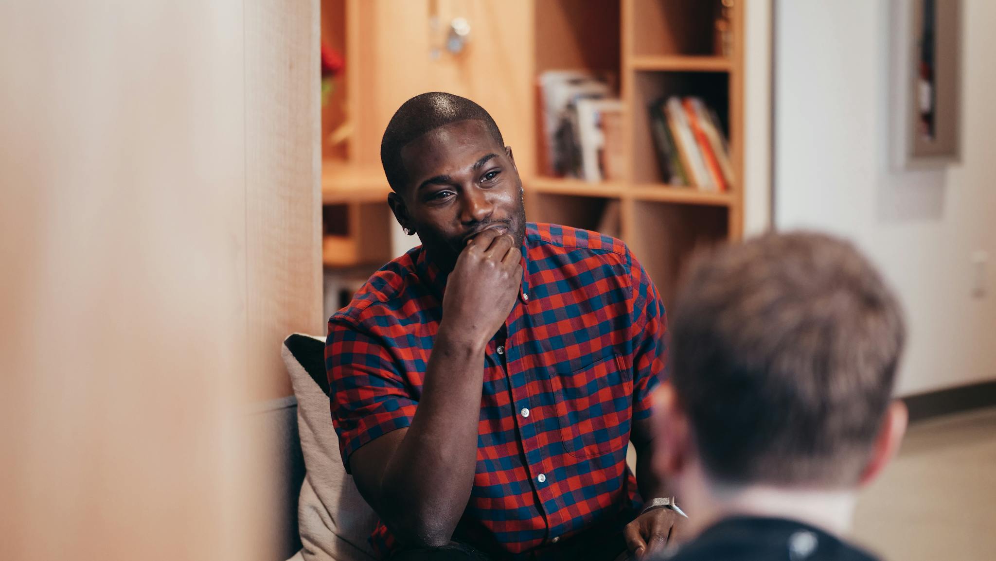 Two adults having a casual conversation indoors with a warm ambiance.