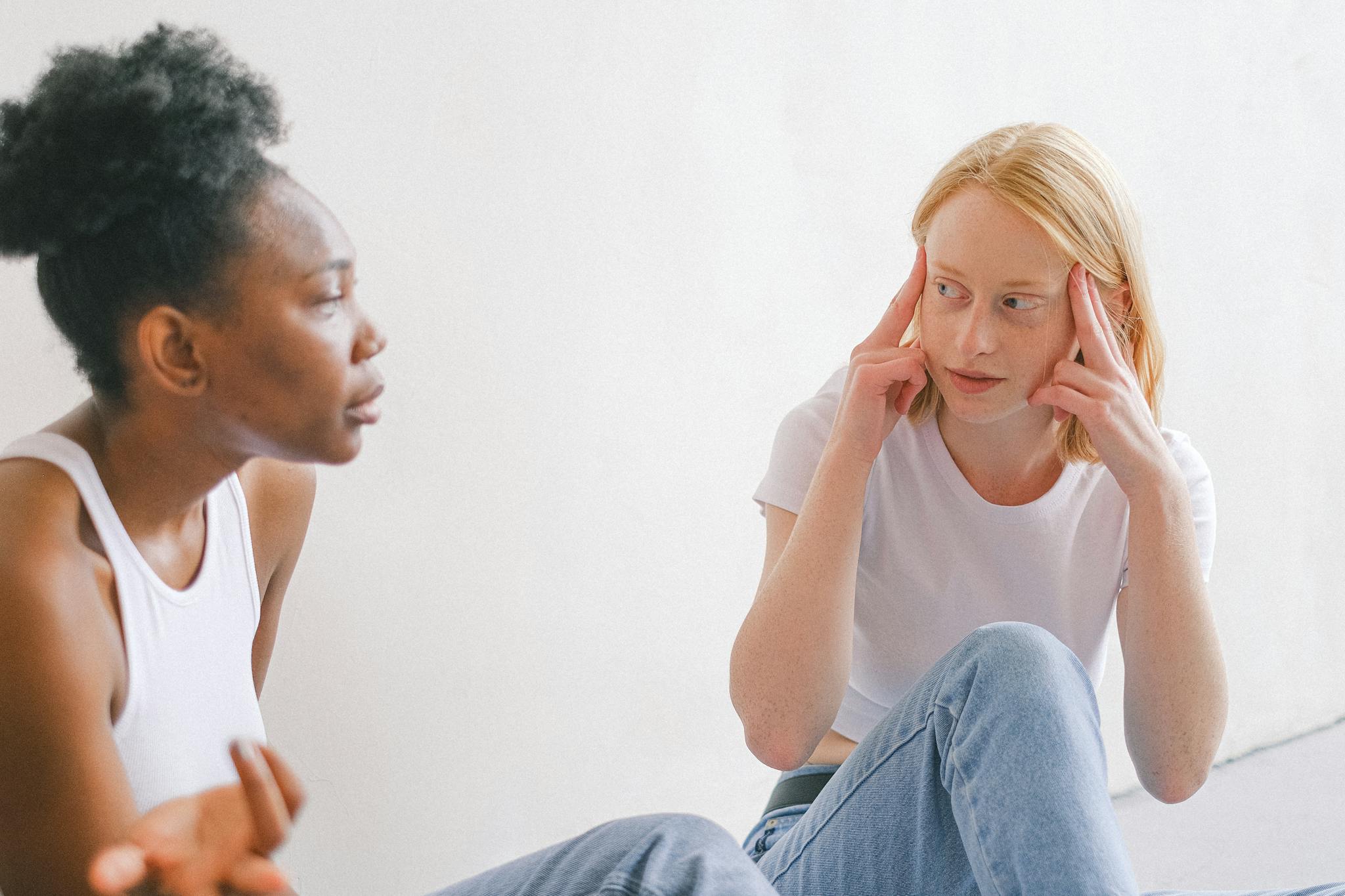 Two women in casual attire having an intense conversation indoors.